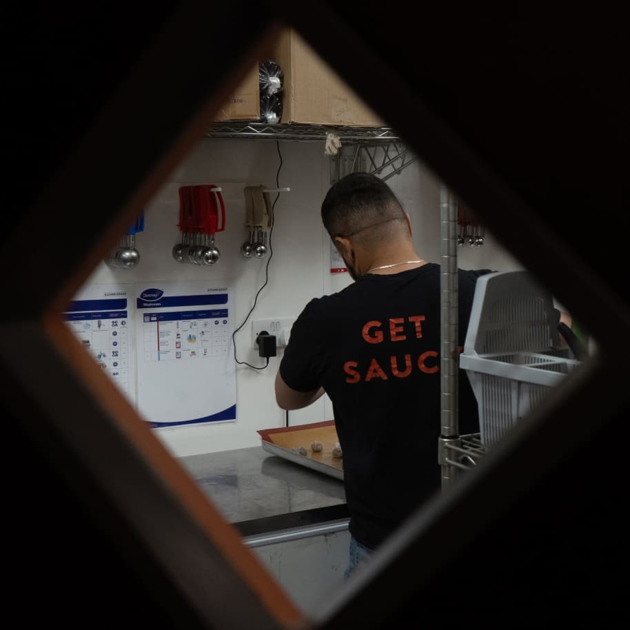 Through a kitchen door a chef prepares food