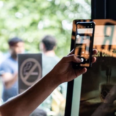 Customer holding up a phone to self order kiosk