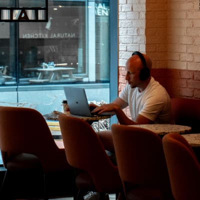 A man sits in Coco di Mama working on laptop