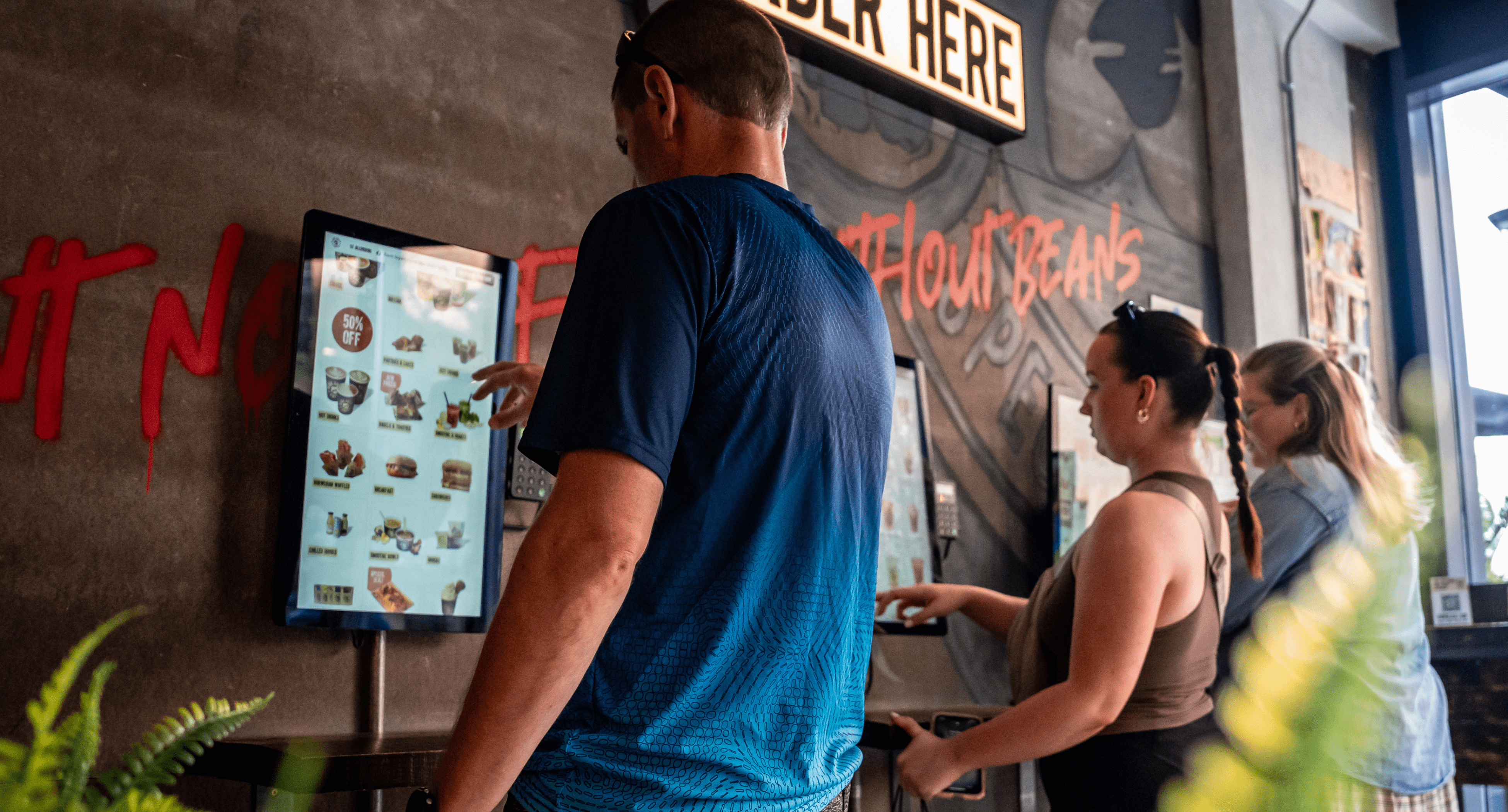 Customers using kiosks in a Black Sheep Coffee