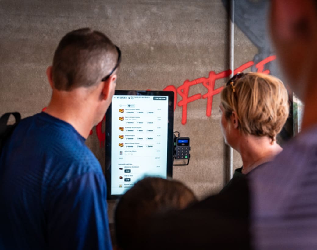 Two people looking at a kiosk screen in a restaurant