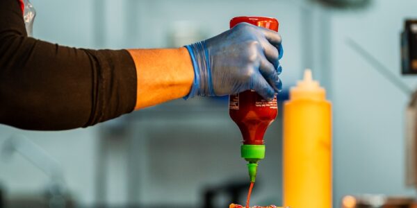 Kitchen staff adding hot sauce to a chicken burger in a Wingers restaurant