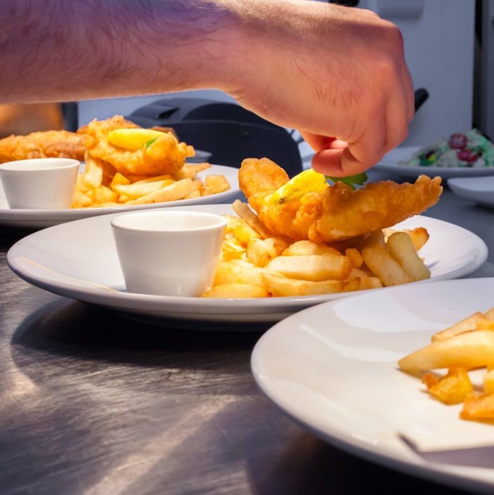 Fish and chips being plated in a Deep Blue restaurant