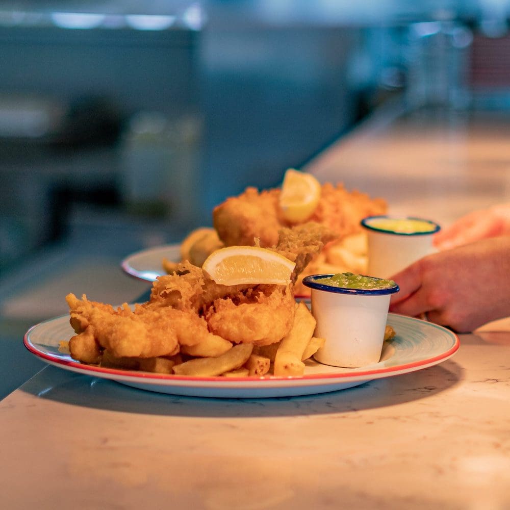 Fish and chips being plated in a Deep Blue restaurant