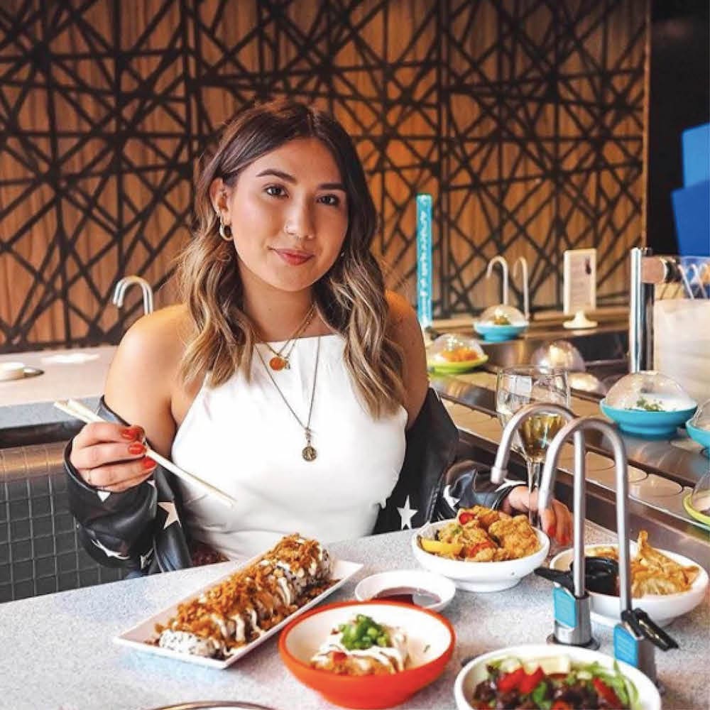 young woman poses while eating sushi